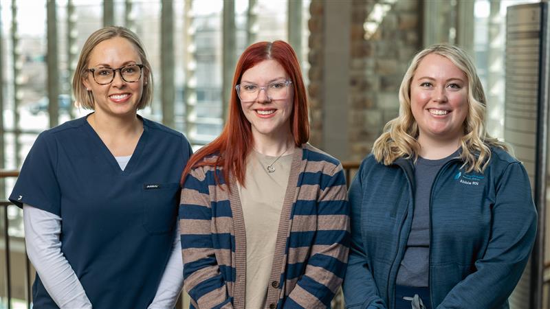 Three Mary Greeley Great Iowa Nurses of 2026 standing together in a hospital setting, dressed in scrubs and business-casual layers.